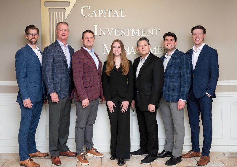 A photo of the Capital Investment Management team standing inside of their office.